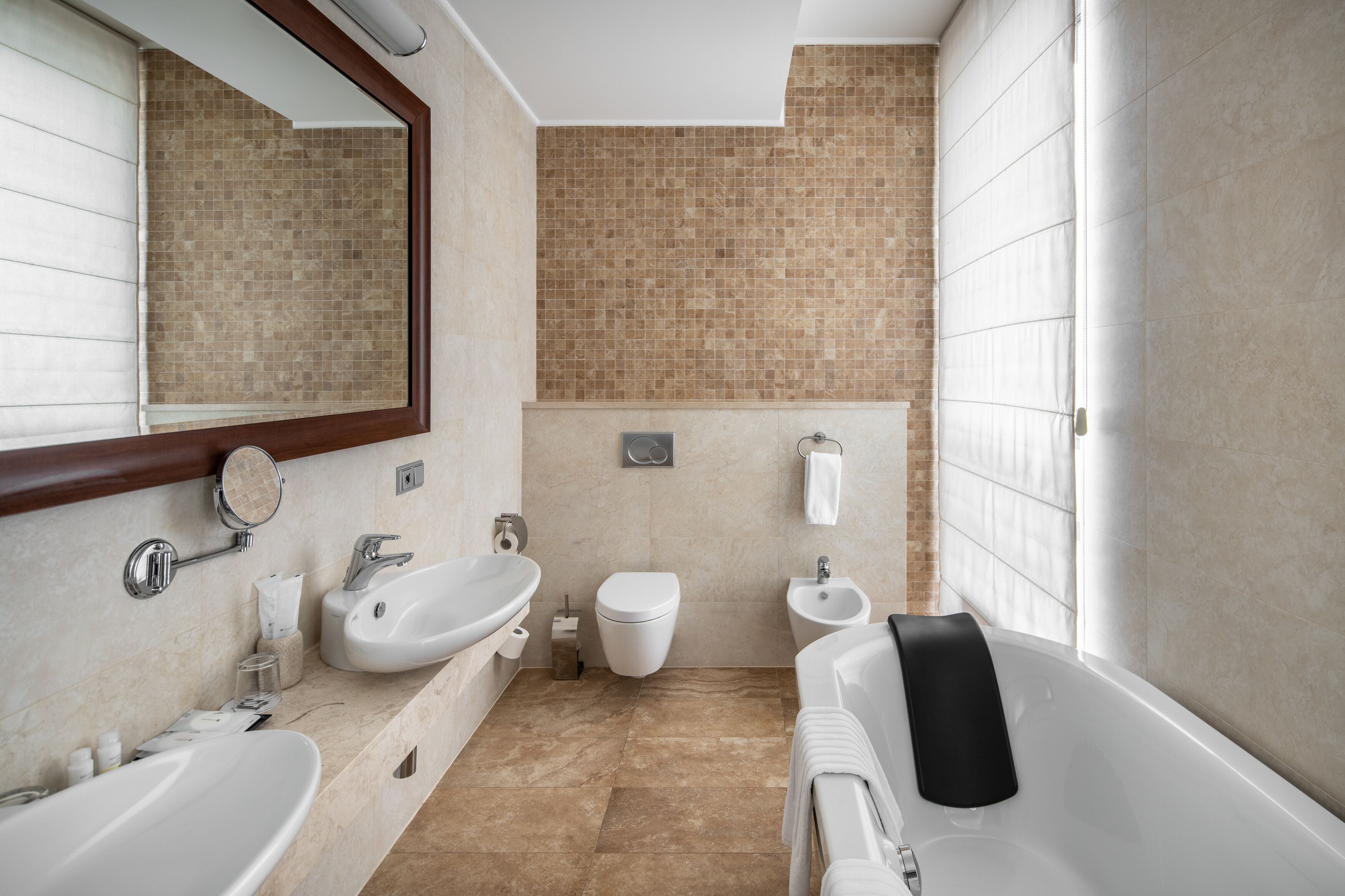 A modern bathroom with two sinks, a toilet, a bidet, and a bathtub.