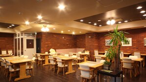 A restaurant with wooden tables and chairs, brick walls, and ceiling lights.