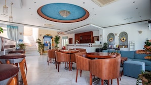 Um amplo hall de hotel com várias áreas de estar, uma escadaria e um balcão de recepção.