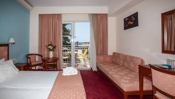 Una habitación de hotel con cama, sofá, escritorio y balcón con vistas.