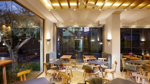 A modern dining area with wooden tables and chairs, large windows, and a ceiling fan. - Annas House (Apokoronas)