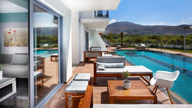 A modern outdoor pool area with lounge chairs and a wooden deck. - Annas House (Apokoronas)