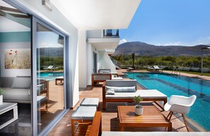 A modern outdoor pool area with lounge chairs and a wooden deck. - Annas House (Apokoronas)