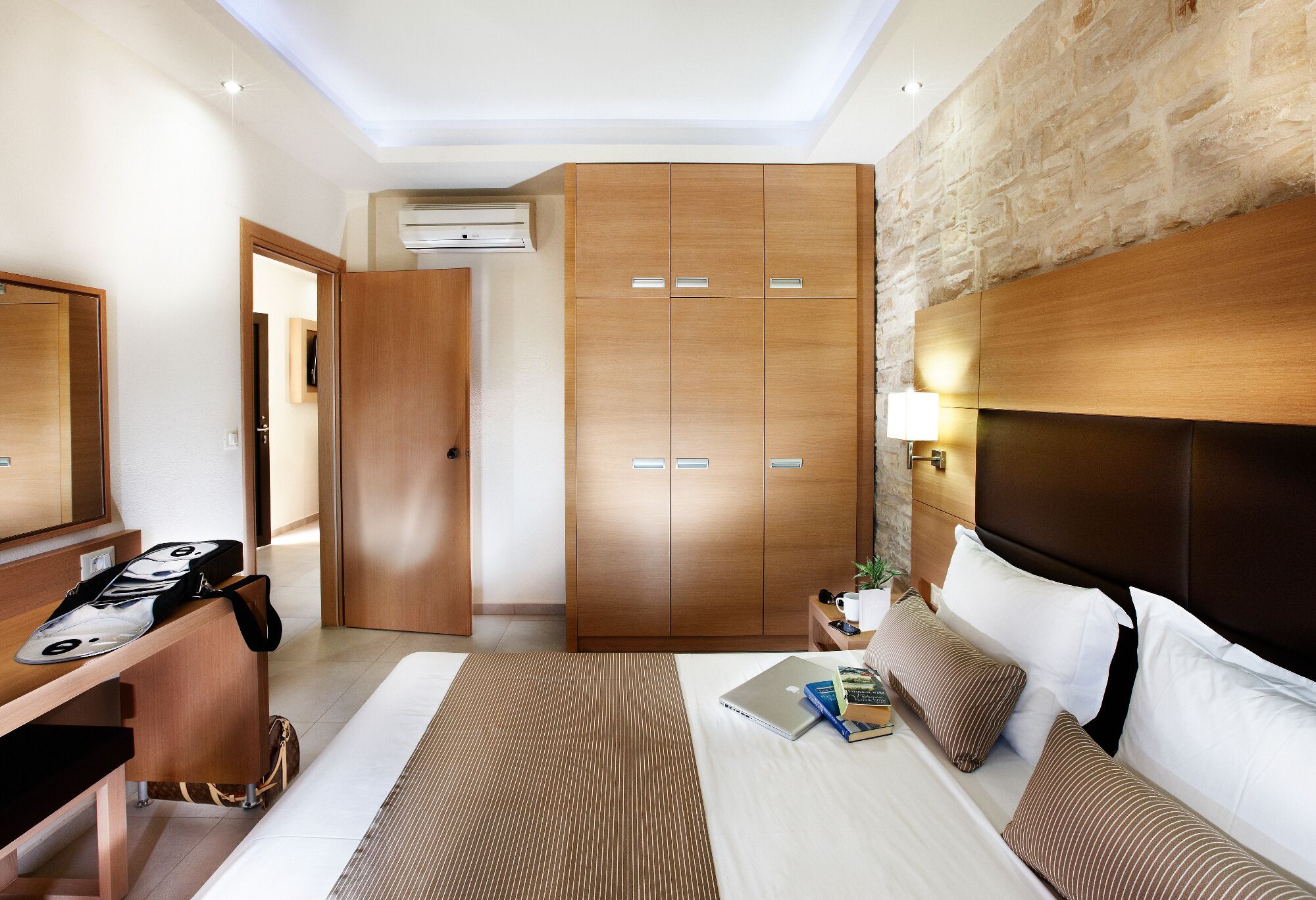 Une chambre d’hôtel comprenant un lit, une table de chevet, une armoire et un bureau avec une chaise.
