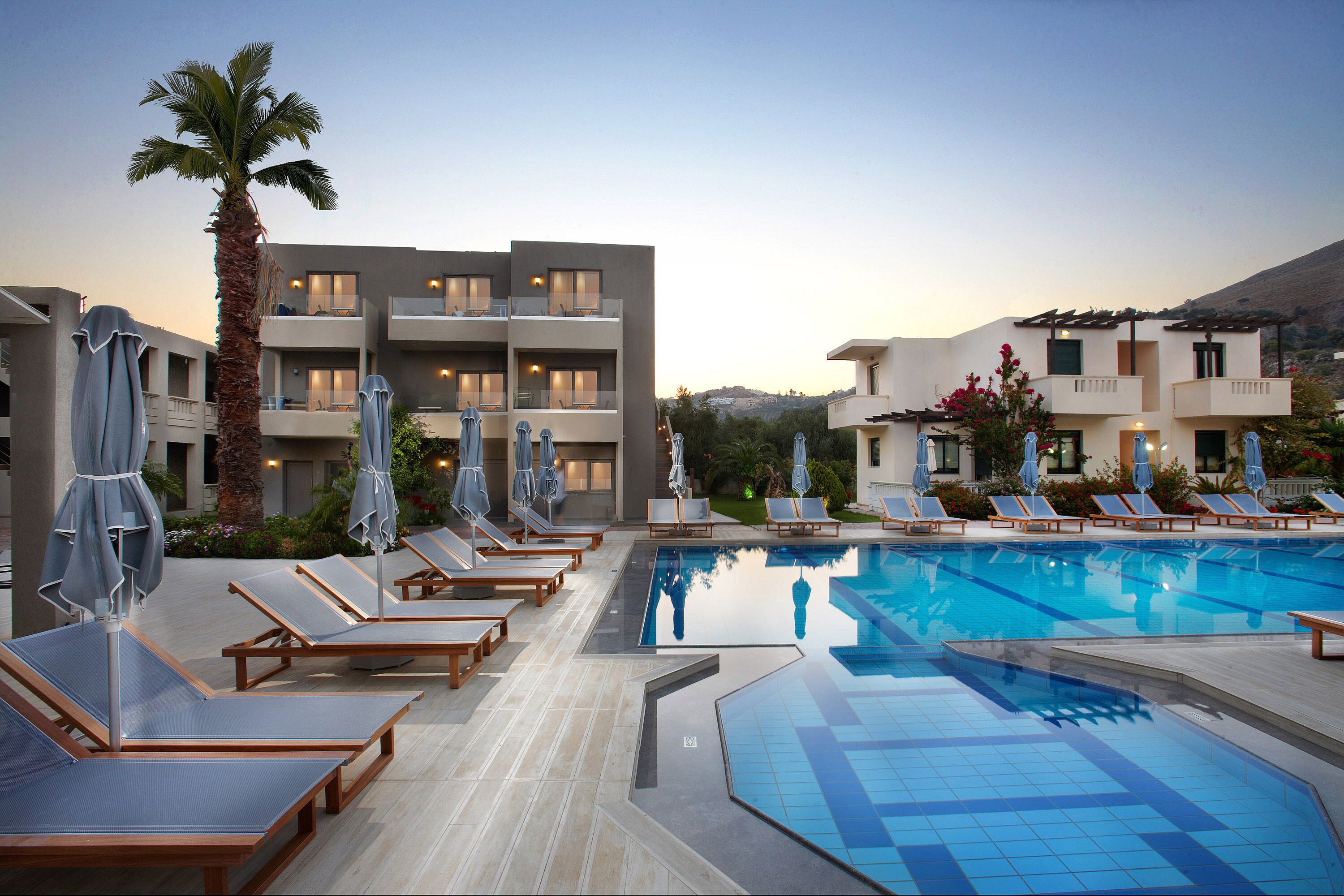 Ein modernes Hotel mit Schwimmbad, Liegestühlen und Sonnenschirmen.
