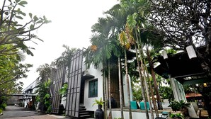 A modern building with a white facade, vertical wooden slats, and a covered outdoor seating area. - Paragon Inn (Bang Phli)