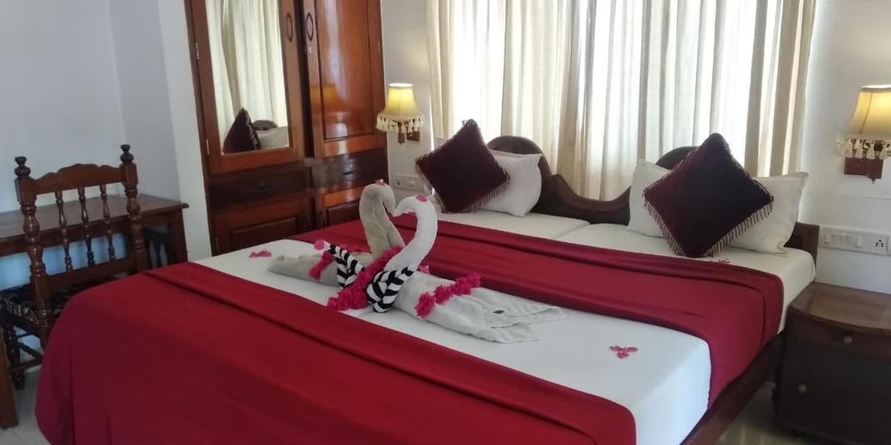 Una habitación de hotel con una cama, una silla de madera, un aparador y un espejo.
