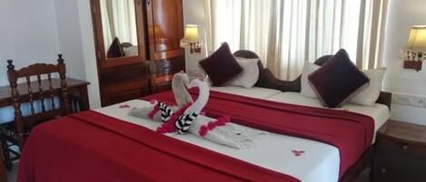Una habitación de hotel con una cama, una silla de madera, un aparador y un espejo.
