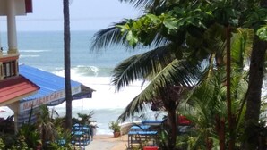 A beachside cafe with a checkered floor, outdoor seating, and a view of the ocean.