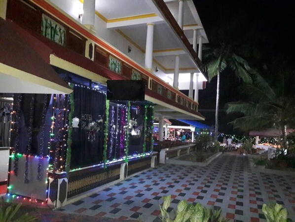 Un hotel con suelo a cuadros, un pasillo cubierto y luces festivas.