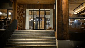 A staircase leading to a building entrance with a wooden interior and a stone wall. - Hotel Bernina (Livigno)