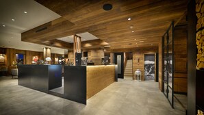 A modern reception area with wooden paneling and a central counter. - Hotel Bernina (Livigno)