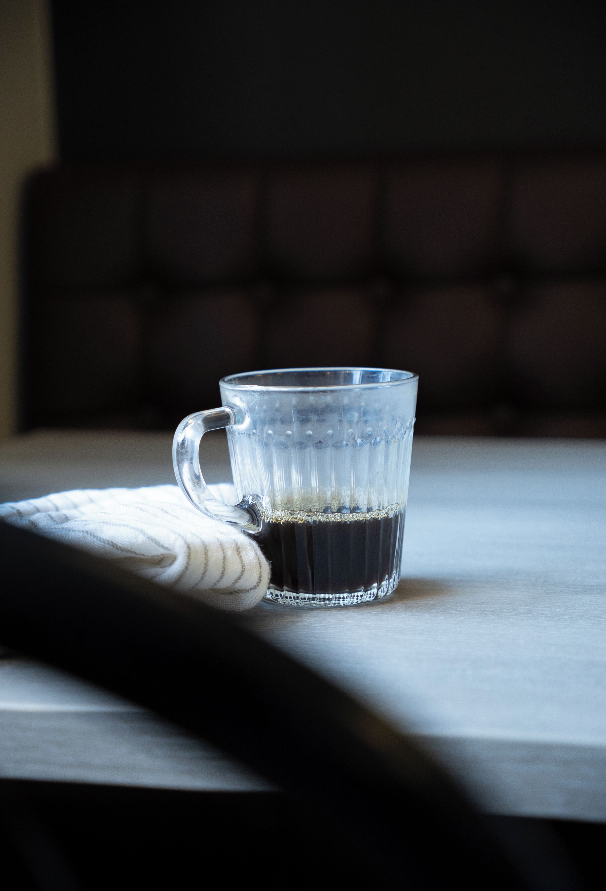 A clear glass mug with a handle on a table.