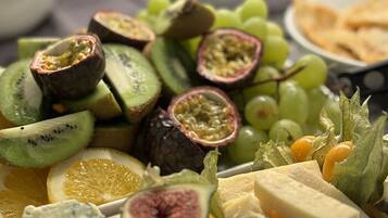 Een schaal met diverse kazen, fruit en sauzen.
