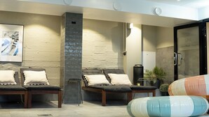 A spa area with two massage chairs, a stone wall, a small heater, and a glass door labeled "SPA". - Hotell Esplanad (Växjö)