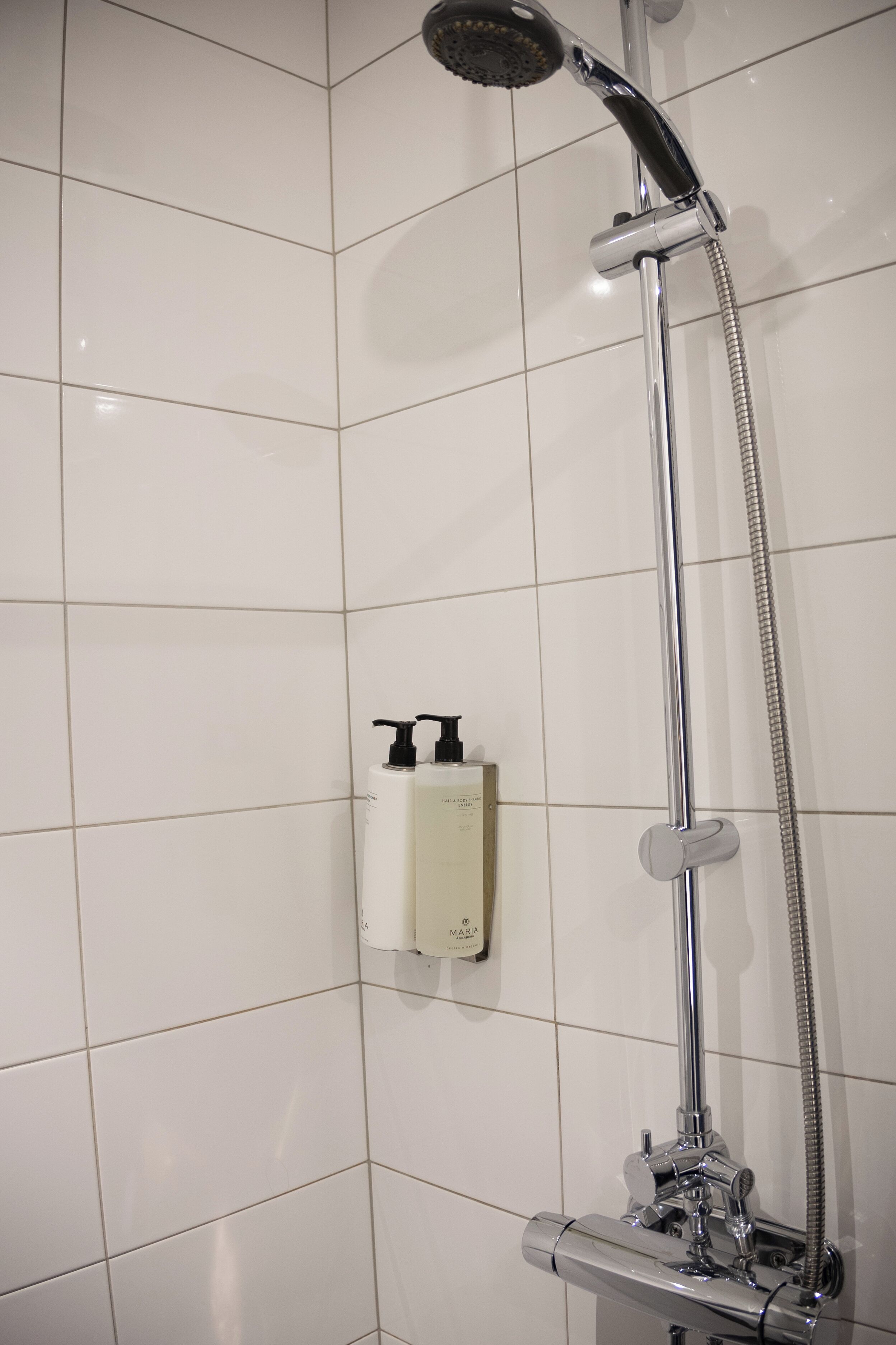 A shower with a handheld showerhead and a wall-mounted faucet.