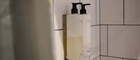 Un baño con paredes de azulejos blancos y un dispensador fijado a la pared.