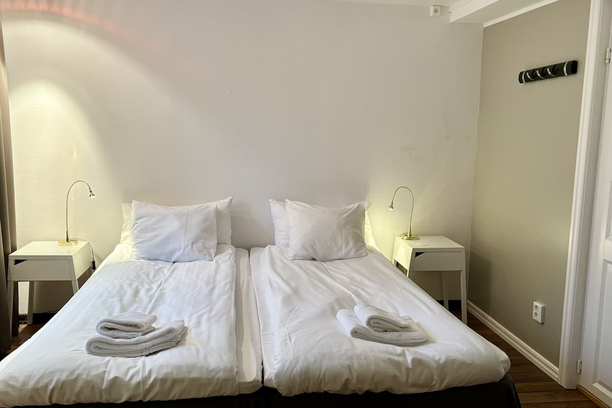 A double bed with white linens and two bedside tables, each with a lamp.