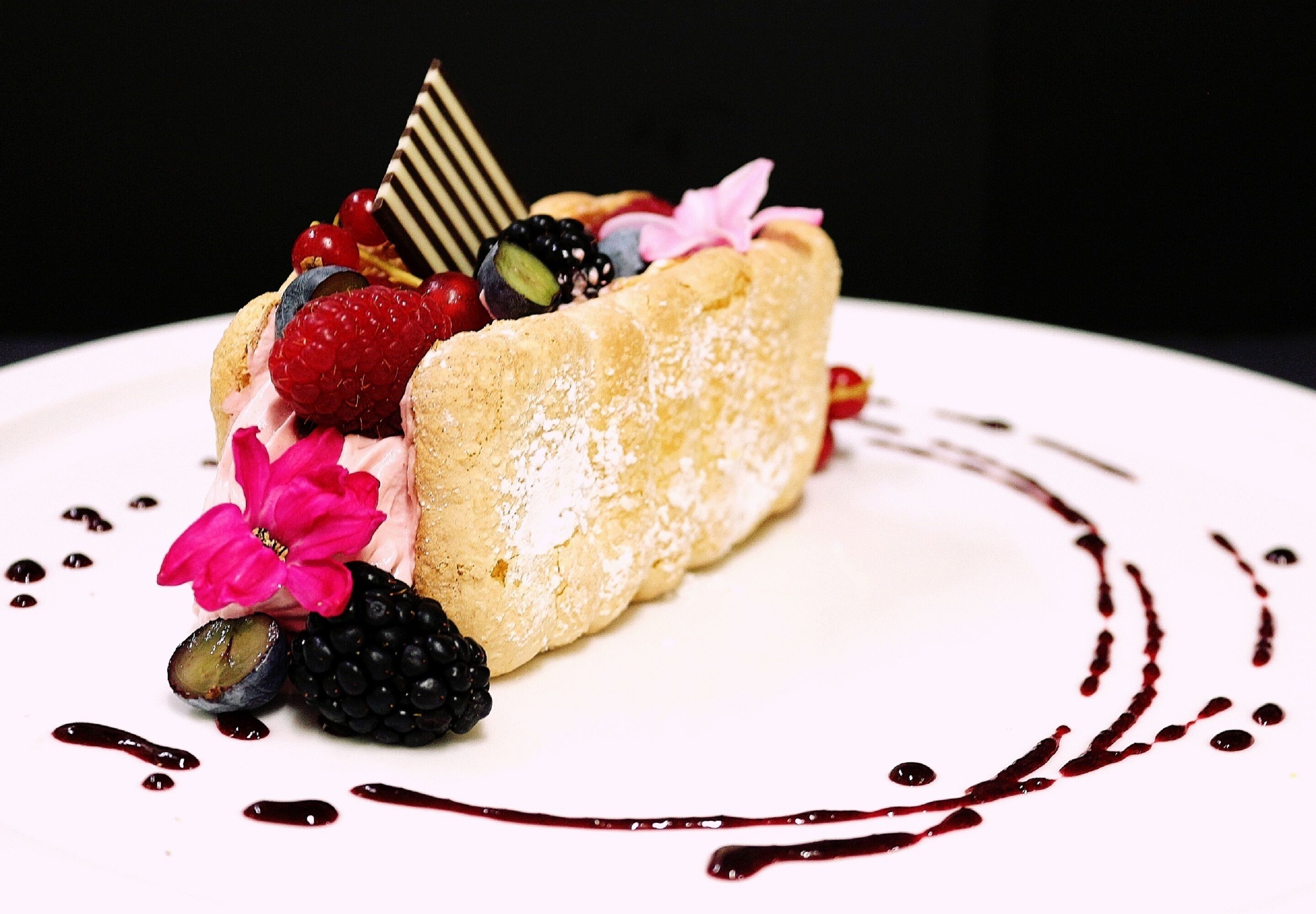 A dessert with berries and a chocolate piece on a plate.