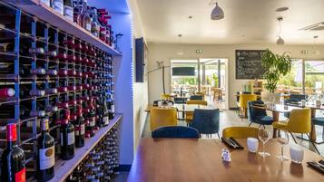 A restaurant with a wine rack, tables, chairs, and a menu board.