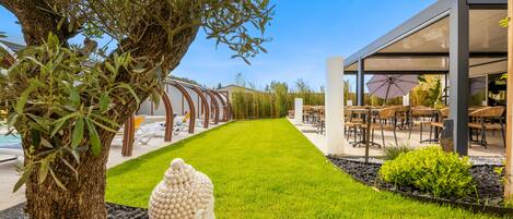 A modern outdoor seating area with a pool, a large white sculpture, and a well-maintained lawn.