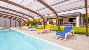 Un área de piscina con sillones de descanso y un porche cubierto.