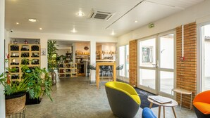 Een modern interieur met zithoeken, een receptiebalie en diverse objecten op planken.