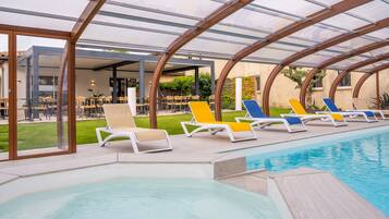 A pool area with lounge chairs and a covered seating area.