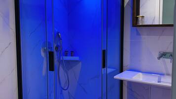 Un baño moderno con ducha de vidrio, lavamanos blanco y piso de mármol.