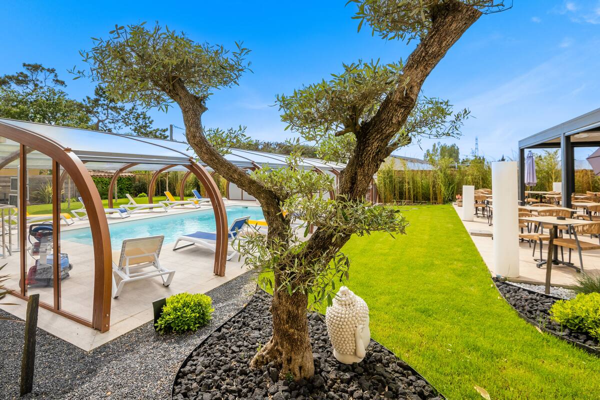 Un área de piscina con sillones reclinables, una zona de estar cubierta y un césped bien cuidado.