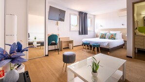 Een moderne hotelkamer met een bed, bureau, stoel en een kleintje tafeltje met een plant.