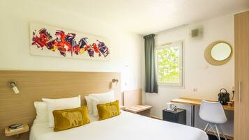 A hotel room with a large bed, a desk, a chair, a window, and a painting on the wall.