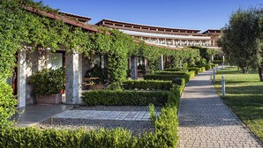 Un patio con un sendero, muros de piedra y follaje.