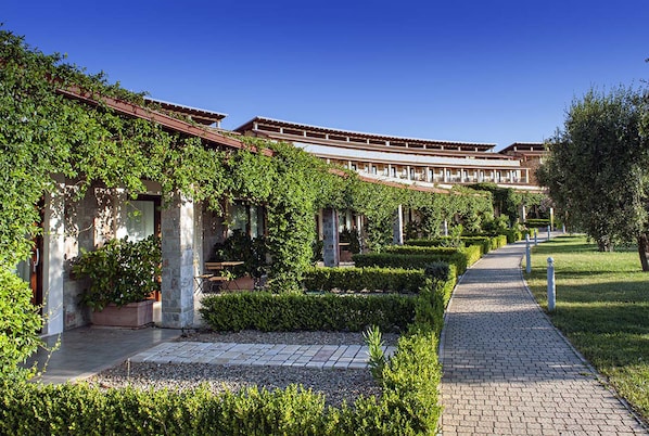 A courtyard with a pathway, stone walls, and greenery.