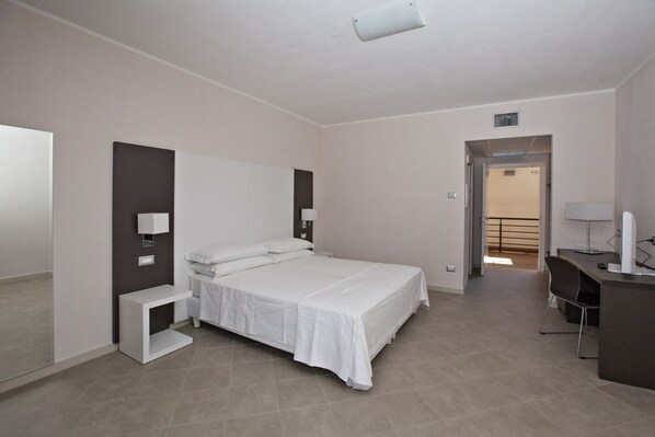 Una habitación de hotel moderna con una cama grande, mesitas de noche, un escritorio y una silla.