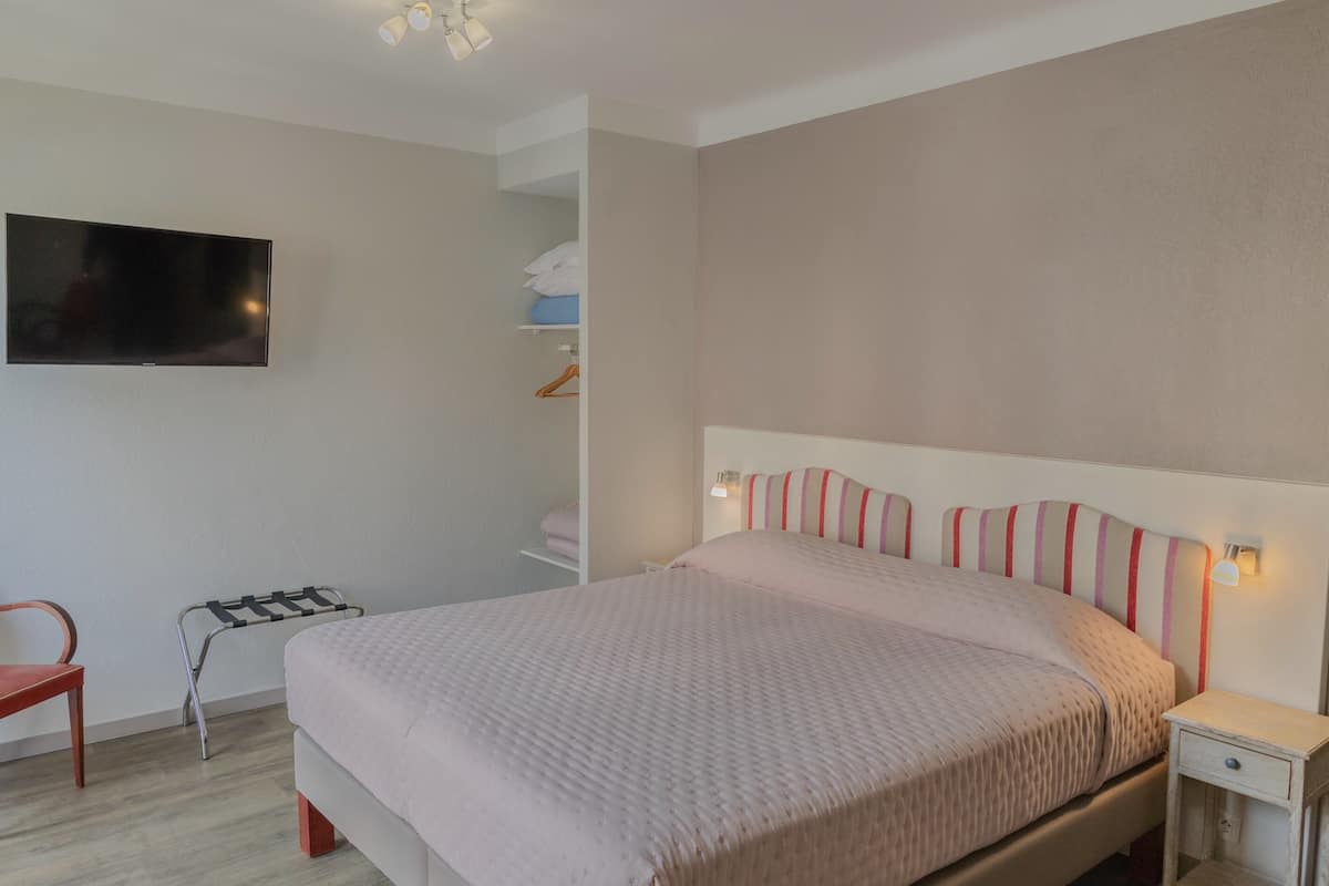A neatly arranged bedroom with a bed, bedside table, and a TV mounted on the wall.