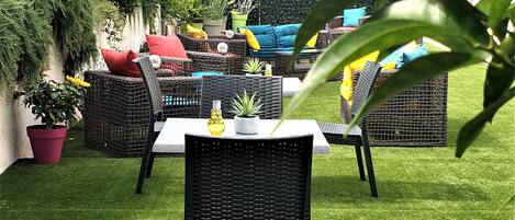 Un espace patio aménagé avec des meubles en osier, une petite table et des plantes en pot.