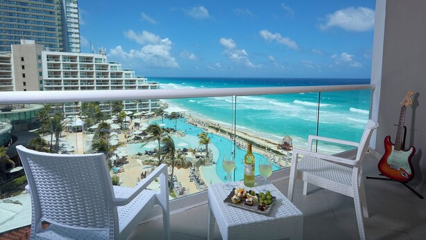 A balcony with a view of a beach resort, including a pool and lounge chairs. - Hard Rock Hotel Cancun -  All Inclusive  (Cancun)