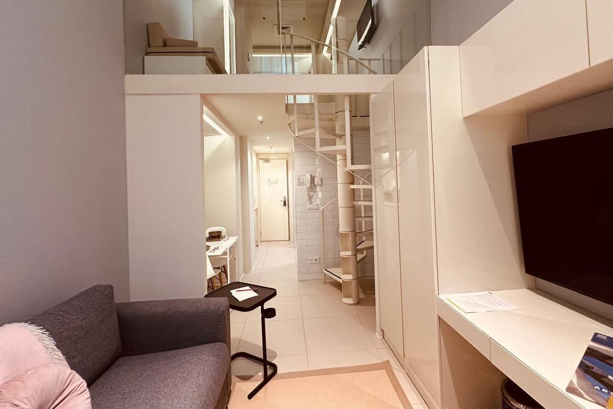 Un apartamento moderno con sala de estar, una escalera y un televisor.