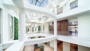 A multi-level atrium with a central open space, wooden flooring, and multiple plant arrangements. - Ortaköy Aparts (Istanbul)