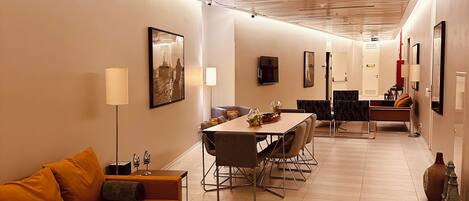 Una habitación de hotel moderna con techo de madera, un área de comedor con una mesa redonda, un sofá y una mesita de centro.
