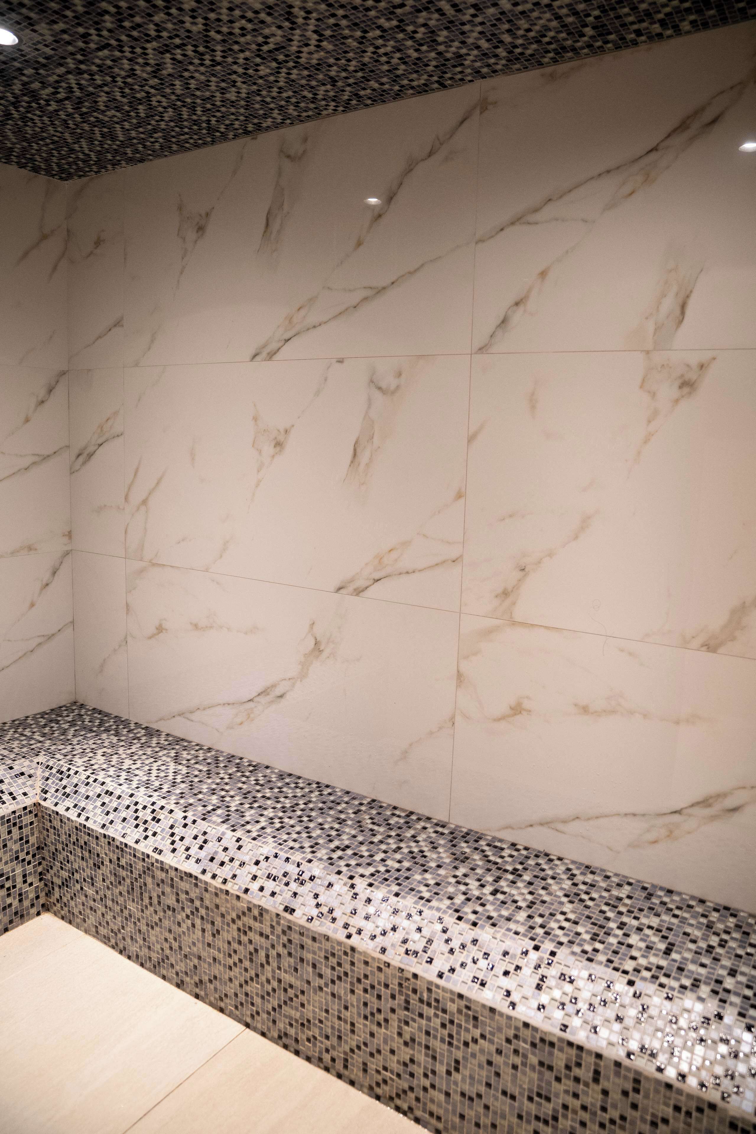 A bathroom with a marble wall and a tiled bench.