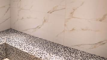 A bathroom with a marble wall and a tiled bench.