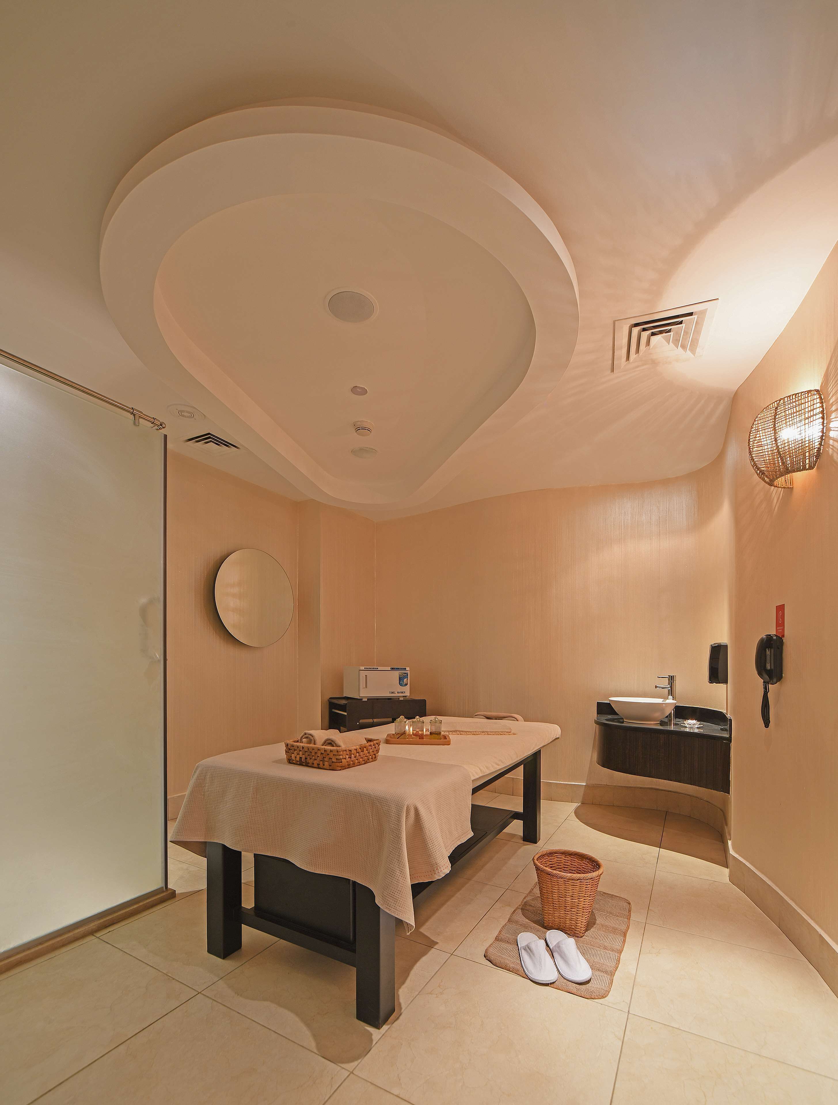 Une salle de spa équipée d’une table de massage, d’un petit lavabo, d’un porte-serviettes et d’un téléphone.