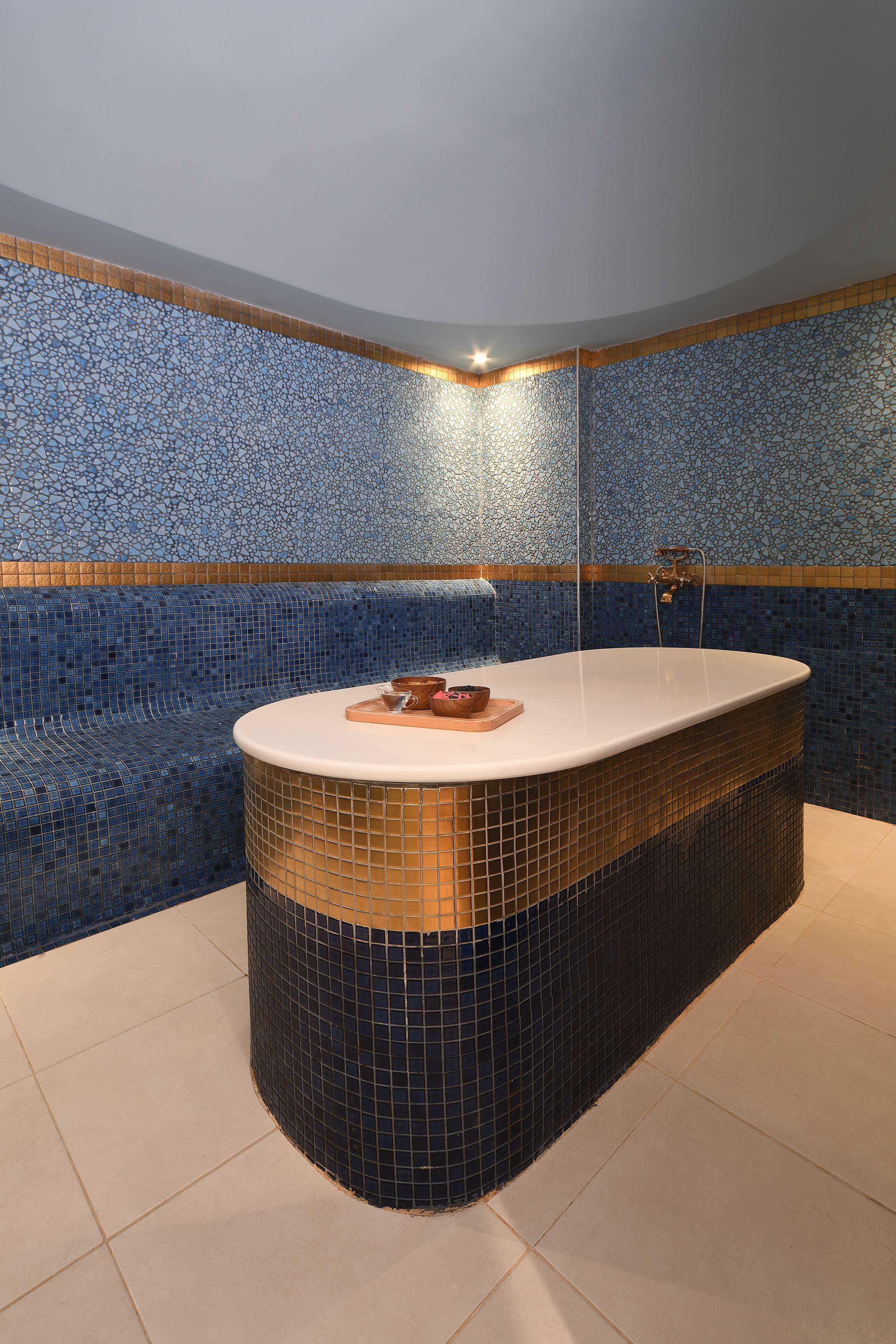 Un área de spa con una bañera grande, paredes de azulejos y un banco.