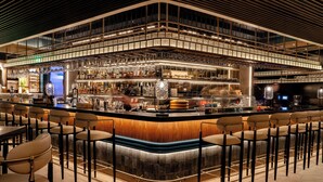 Un espace bar moderne doté d’un comptoir incurvé, de nombreux types de sièges et d’une variété de bouteilles et de verres exposés.