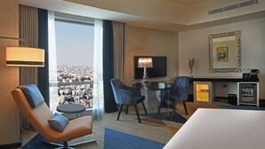 Une chambre d’hôtel dotée d’une grande fenêtre, d’un téléviseur à écran plat, d’un minibar et d’un lit.