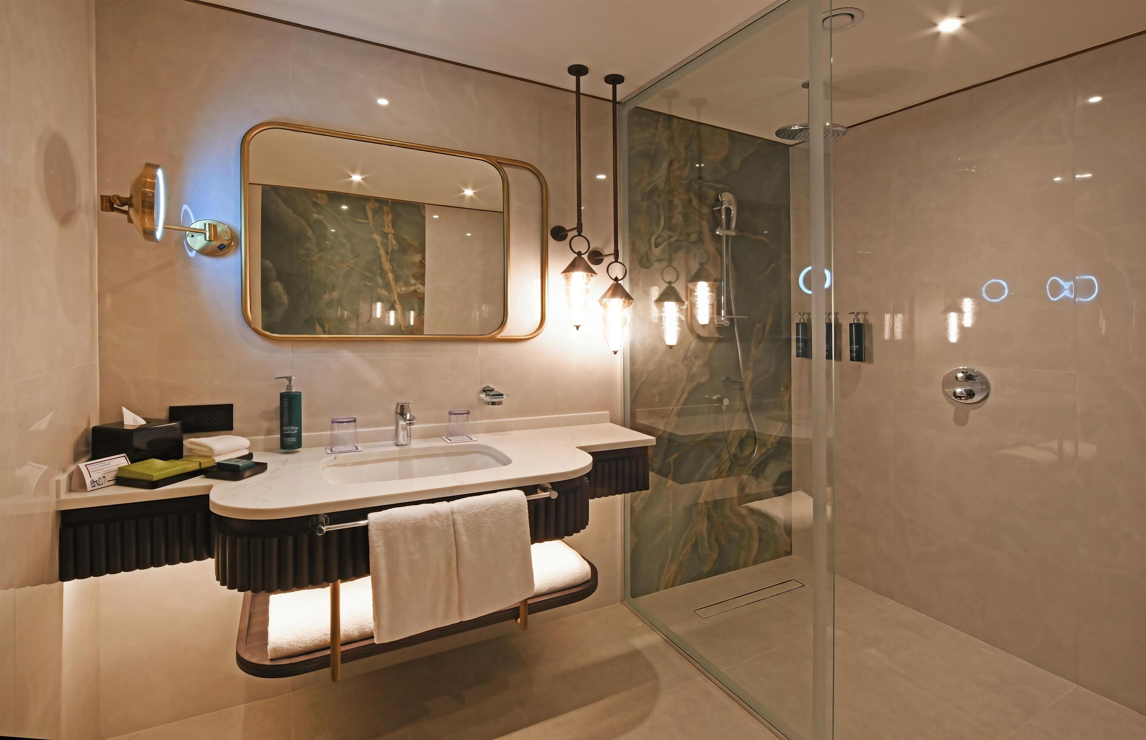 A modern bathroom with a glass-enclosed shower, a large mirror, and a vanity with a dual sink.