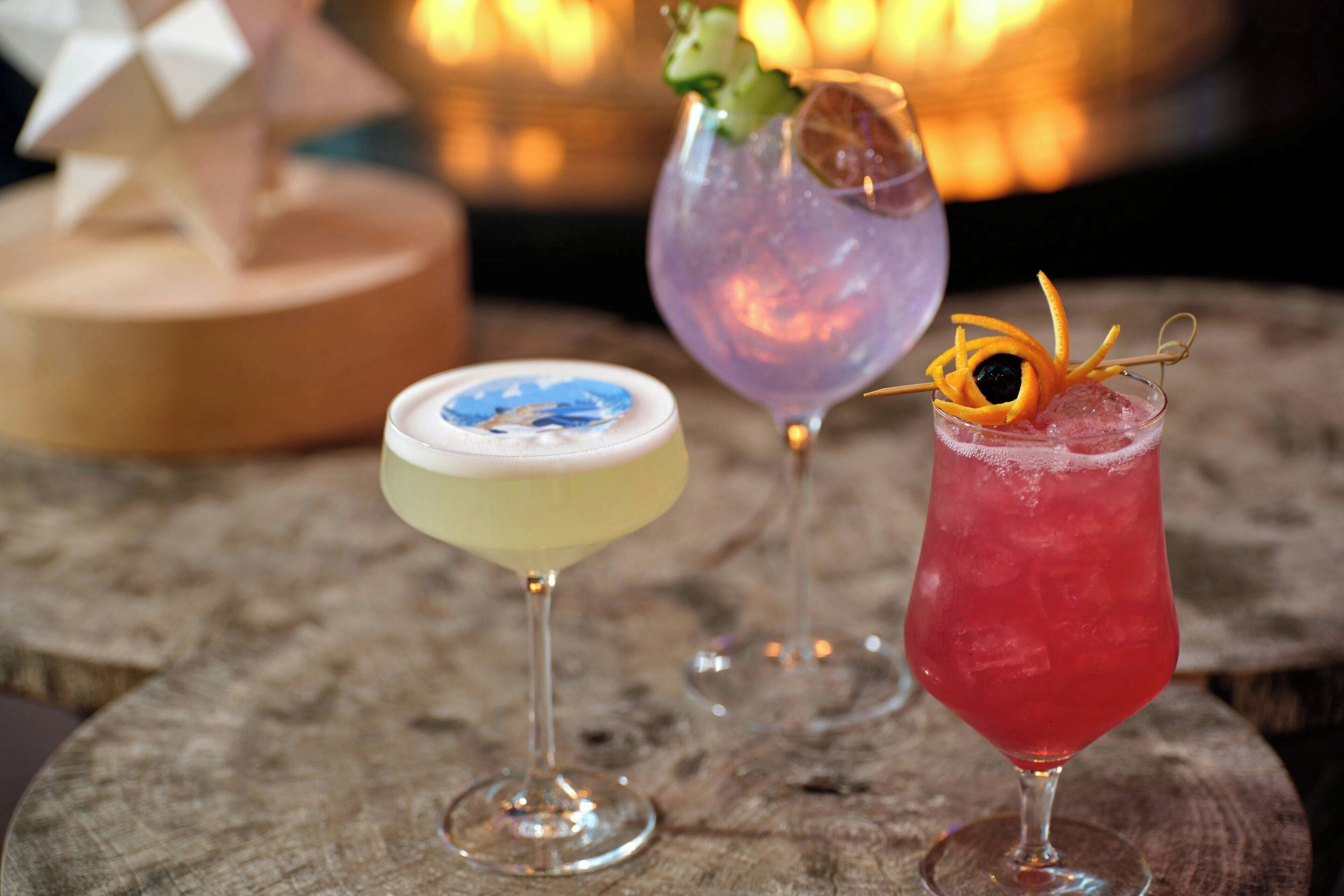Trois cocktails sur une surface en bois, avec un arrière-plan flou.