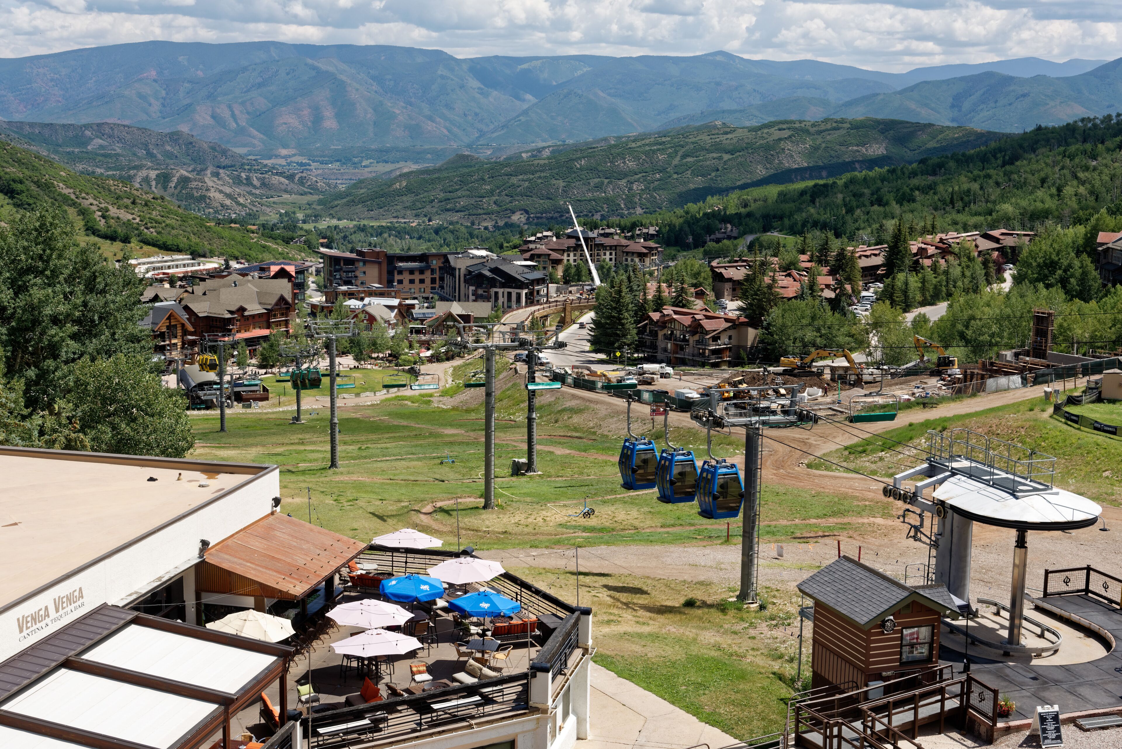 A mountain resort with multiple buildings, outdoor seating, and a cable car system.